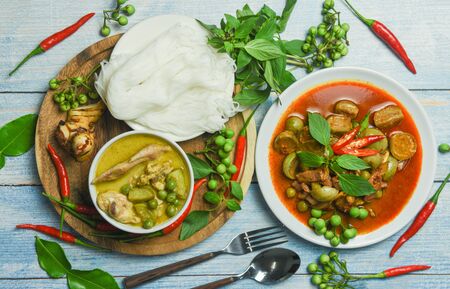 Set of Thai food green curry on soup bowl and red curry on plate with thai rice noodles vermicelli ingredient herb vegetable on wooden background / green curry chicken cuisine asian food on the tableの写真素材