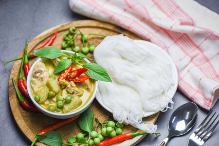 Thai food green curry chicken on soup bowl and thai rice noodles vermicelli with ingredient herb vegetable / asian food on the tableの写真素材