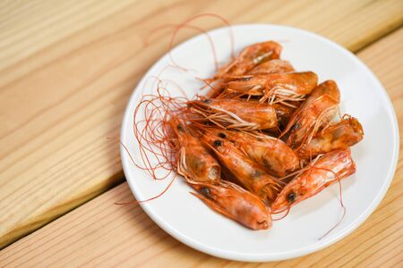 Deep fried crispy shrimp head delicious seasoning spices on plate and wooden table background / cooked shrimps or prawns , Seafood shelfishの写真素材