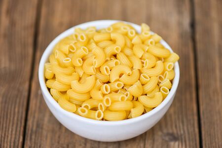 macaroni top view on bowl and wooden background close up raw macaroni uncooked delicious pasta or penne noodlesの写真素材