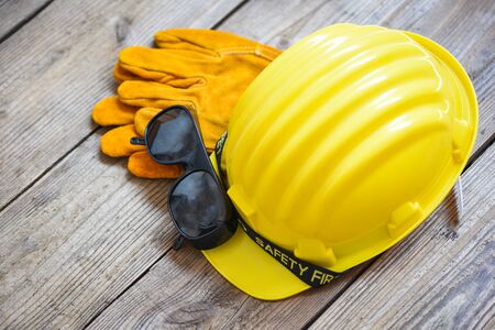 Safety equipment standard construction safety / Industrial protective workwear tool with yellow hat safety helmet glasses and gloves on wood background , top view の写真素材