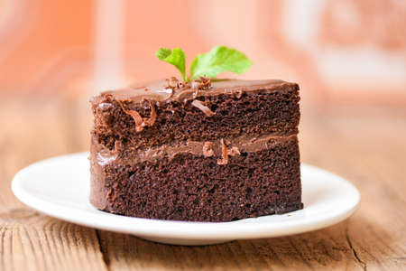 Cake chocolate delicious dessert served on the table / cake slice on white plate with topping chocolate and mint leafの写真素材