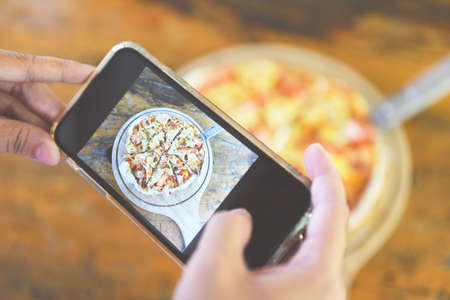 Food photography woman hands make photo Pizza with smartphone / taking photo food for post and share...