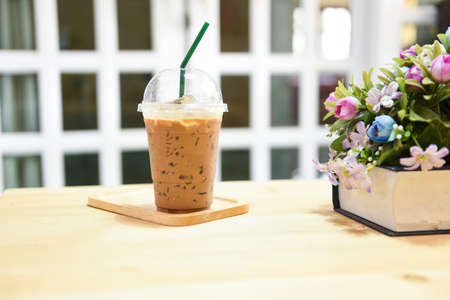 coffee plastic cup on wooden table background / plastic glass of iced coffee with milk