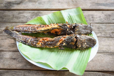catfish roasted on banana leaf / cooked catfish grilled Asian food on wooden table