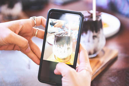 Food photography woman hands make photo cocoa drink and cake with smartphone / taking photo food for...