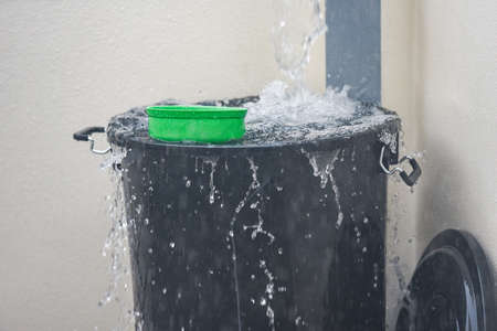 Bucket with water splashes rain water harvesting in the bucket of water after rainの写真素材