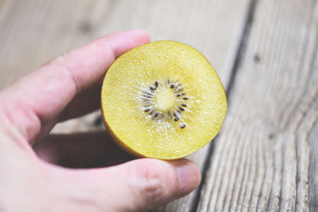 Kiwi slice on wooden background, kiwi fruit in handの写真素材