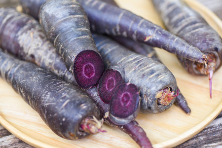 purple carrot on wooden plate , fresh carrot for cooking vegetarian on wooden tableの写真素材
