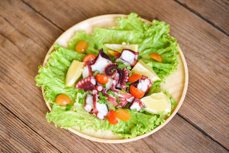 Octopus salad with lemon tomatoes and vegetables on wooden plate Fresh and healthy salad seafood squid and octopusの写真素材