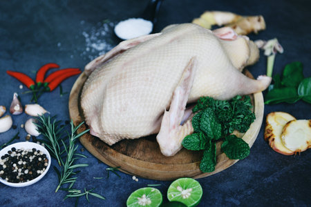 Fresh duck meat on wooden tray for food, Raw duck with herb spices ready to cook on dark palte, Whole duck - top viewの写真素材