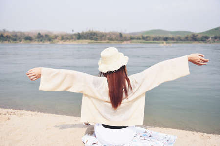 Woman on the beach concept, Young pretty woman in hat tropical beach sea island in the background. Beautiful vacation summer holiday fashion, girl on the riverの写真素材