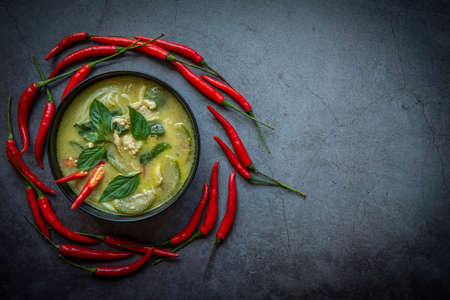 Chicken green curry Thai food on soup bowl with ingredient vegetable herbs and spices pepper chili dark background, Traditional green curry chicken cuisine asian food. Top viewの写真素材