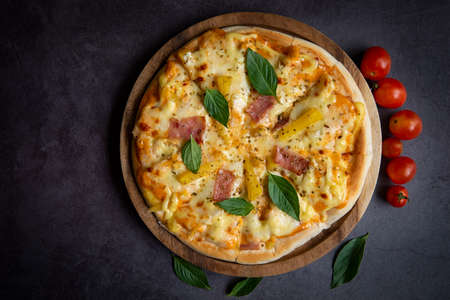Tasty pizza homemade italian food style, pizza cheese ham and pineapple fruit cooking ingredients tomatoes basil on black background, Top view of pizza cheese italian food style. Flat layの写真素材