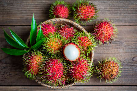 Fresh and ripe rambutan sweet tropical fruit peeled rambutan with leaves, Rambutan fruit on basket and wooden background harvest from the gardenの写真素材