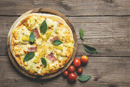 Tasty pizza homemade italian food style, pizza cheese ham and pineapple fruit cooking ingredients tomatoes basil on wooden background, Top view of pizza cheese italian food style. Flat layの写真素材