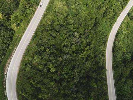 Aerial view forest nature with car on the road on the mountain green tree, Top view road curve from above, Bird eye view road through mountain the green forest beautiful fresh environmentの写真素材