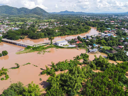 Aerial view river flood village countryside Asia and forest tree, Top view river with water flood from above, Raging river running down jungles lake flowing wild water after the rainの写真素材