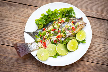 Steamed tilapia fish with chili and lime lemon sauce with herb and Vegetable on plate, Fish steam lime - Thai foodの写真素材