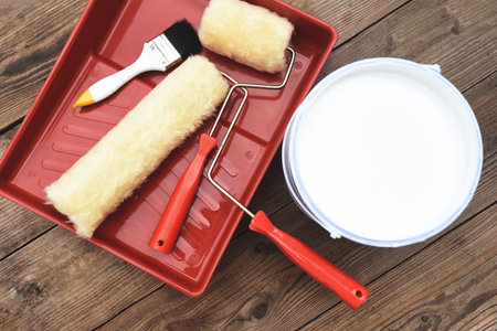 Painted tool with roller paint brush paint bucket canned paint for painting on wooden background, top view on paint trayの写真素材
