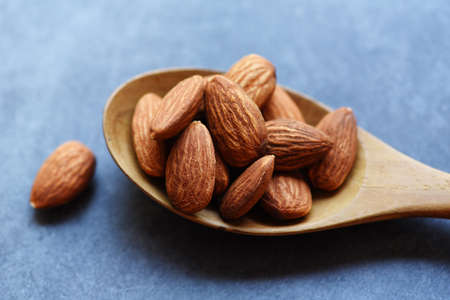 Almonds on wooden spoon and dark background top view on the table, Close up roasted almond nuts natural protein food and for snackの写真素材