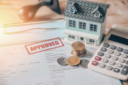 Home loan approved on loan application form paper with rubber stamp calculator coin and loan house...
