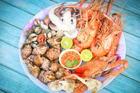 seafood plate with shrimp shellfish crab squid cockle spotted babylon with seafood sauce chili lemon lime serve on dining table, shrimps prawns seafood buffet menu cooked foodの写真素材