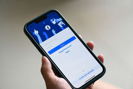 Facebook application icon on Apple iPhone 13 Pro, holding smartphone with login home page facebook logo icon on the screen popular social media network from Meta, : Bangkok, Thailand - June 3 2022のeditorial素材