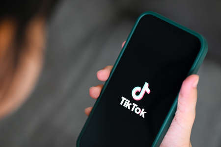 Child holding smartphone with TikTok application icon on Apple iPhone 13 Pro, Tiktok logo icon on the screen popular social media network from china, : Bangkok, Thailand - June 3 2022のeditorial素材
