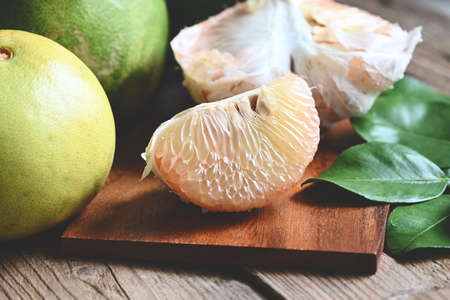 pomelo fruit on wooden plate  background, fresh green pomelo peeled and leaf frome pomelo tree , pummelo , grapefruit in summer tropical fruit  in thailandの写真素材