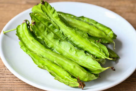 Winged Bean on white plate background, Psophocarpus tetragonolobus - Green winged or Four angle beansの写真素材