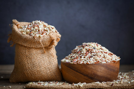 brown rice on wooden bowl and in the sack with dark background , raw various rice color mixed thai rice for cooking food , Loonzain rice brown black red white purple health food.の写真素材