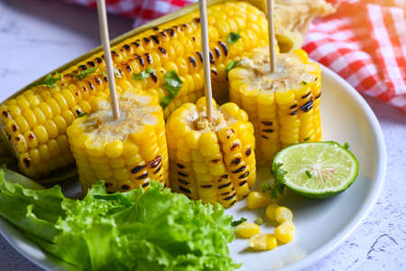 sweet corn food with salad vegetable lime coriander and lettuce, sweet corn cooked on white plate background, ripe corn cobs grilled sweetcorn for food vegan dinner or snackの写真素材