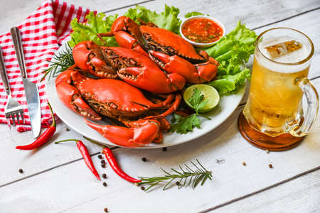 seafood plate with herbs spices rosemary lemon lime salad lettuce vegetable, fresh crab on white plate seafood sauce and mug beer glass, crab cooking food boiled or steamed crab red in the restaurantの写真素材