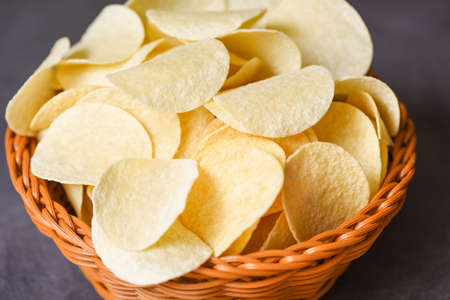 Crispy potato chips on the food table black background, Potato chips snack on basketの写真素材