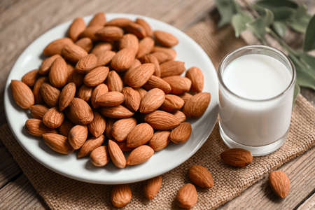 Almond milk and Almonds nuts on on white plate background, Delicious sweet almonds on the table, roasted almond nut for healthy food and snackの写真素材