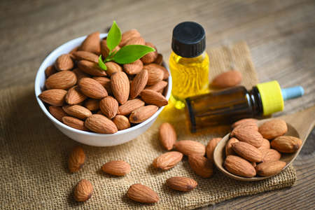 Almond oil and Almonds nuts on bowl, Delicious sweet almonds oil in glass bottle, roasted almond nut for healthy food and snack organic vegetable oils for cooking or spa conceptの写真素材