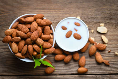 Almond milk and Almonds nuts on on wooden background, Delicious sweet almonds on the table, roasted almond nut for healthy food and snack - top viewの写真素材