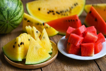 Red and yellow watermelon slice on plate and wooden background, Closeup sweet watermelon slices pieces fresh watermelon tropical summer fruit - top viewの写真素材