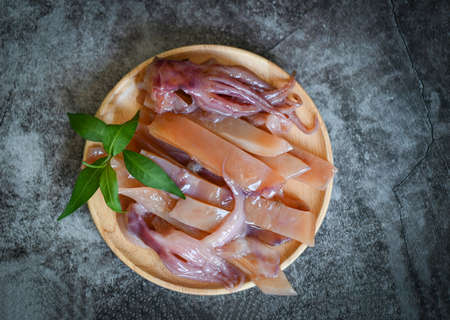 pickled squid on plate, raw squid for cooking food on dark background, preserving food seafood - top viewの写真素材