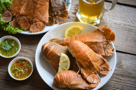 Fresh slipper lobster flathead boiled cooking with parsley rosemary in the restaurant, Flathead lobster shrimps served on white plate seafood sauce and mug beer glass, Rock Lobster Moreton Bay Bugの写真素材