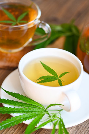 Cannabis tea herbal on tea cup with cannabis leaf marijuana leaves herb on wooden background, health tea with hemp leaf plant THC CBD herbs food and medical conceptの写真素材