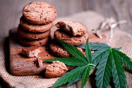 delicious sweet dessert cookie with hemp leaf plant THC CBD herbs food snack and medical, Cannabis food cookies with cake chocolate cannabis leaf marijuana herb on wooden backgroundの写真素材