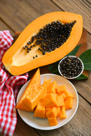 papaya fruits on wooden backgroud, fresh ripe papaya slice on white plate tropical fruit with papaya seed and leaf leaves from papaya treeの写真素材