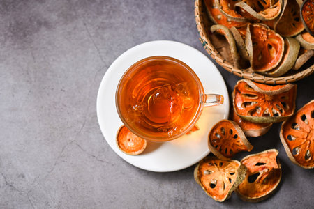 Bael tea on glass with dried bael slices on dark background, Bael  juice - Dry bael fruit tea for...