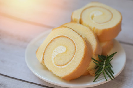 Cake roll on plate cake with rosemary on table, sponge cake roll slices sweets dessert cream roll...