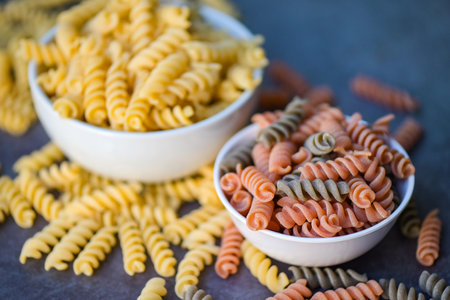 Pasta raw macaroni on white bowl background, close up raw macaroni spiral pasta uncooked delicious whole grain fusilli pasta for cooking foodの写真素材