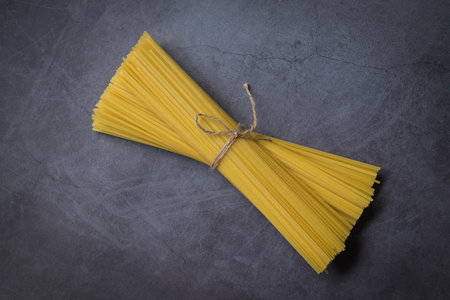 Raw spaghetti pasta uncooked, spaghetti noodles on dark background, raw pasta italian food - top viewの写真素材
