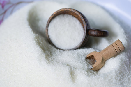 Sugar with cup and wooden scoop, white sugar for food and sweets dessert candy heap of sweet sugar crystalline granulatedの写真素材