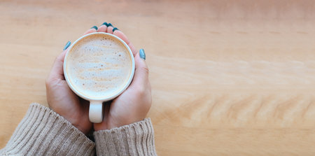top view coffee caramel woman coffee with hand holding a cup on the wood table, caramel coffee cup...